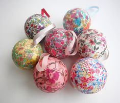 an assortment of colorful decorated balls with ribbons on white table top, next to each other