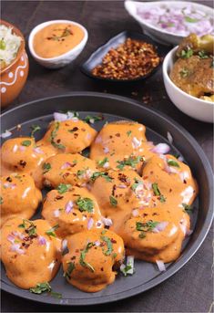 some food is on a black plate with sauces and other dishes in the background