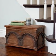 a wooden trunk sitting on top of a hard wood floor next to a stair case