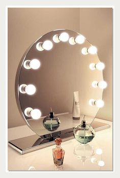 a lighted mirror sitting on top of a table next to a perfume bottle and vase