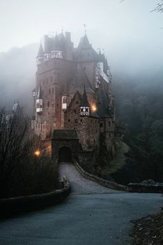 an old castle is lit up in the fog