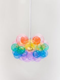 a multicolored bird feeder hanging from a white ceiling with balloons attached to it