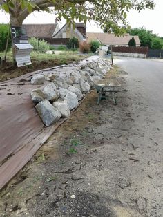 a bench sitting next to a large pile of rocks on the side of a road