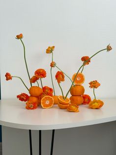 an arrangement of oranges and flowers on a table