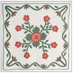 a white quilt with red and yellow flowers in the center, on a green border