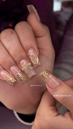 a woman's hand with some gold and pink nail polishes on her nails