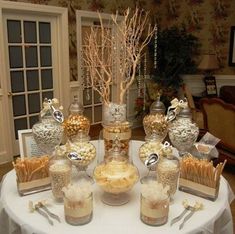 a table topped with lots of desserts and candies on top of a white table cloth