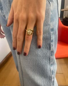 a woman's hand with a gold ring on her left wrist, and an orange chair in the background