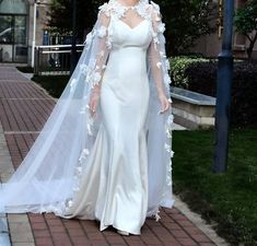 a woman is walking down the street wearing a wedding dress