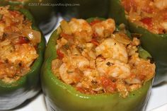 several green peppers with shrimp and rice in them on a white plate, ready to be eaten