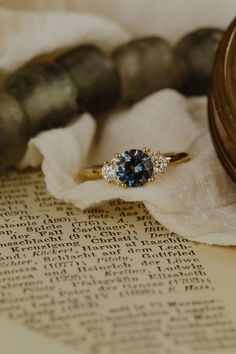 a blue diamond ring sitting on top of an old book