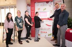 several people are standing in front of a red and white sign that says cosmetic spa