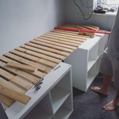 a person standing in front of a bed with wooden slats on top of it