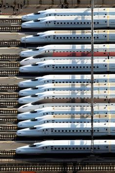 a large group of white and red trains parked next to each other on train tracks