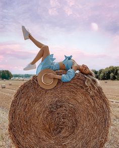 a woman laying on top of a hay bale