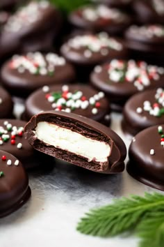 chocolate covered cookies with white frosting and sprinkles are on a table