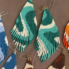 beaded earrings with different colors and shapes on top of a gray surface, next to each other