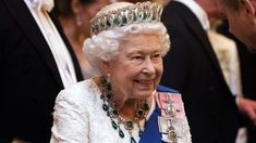 an older woman wearing a tiara and smiling at the camera with other people behind her