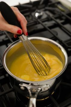 a woman whisks eggs into a sauce in a pan on the stove top