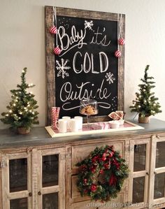 a buffet table with christmas decorations on top and a chalkboard sign above it that says baby it's cold outside