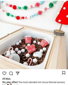 a wooden box filled with marshmallows and candy canes next to a christmas tree