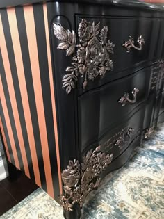 an ornate black and gold painted dresser with flowers on it's side paneling