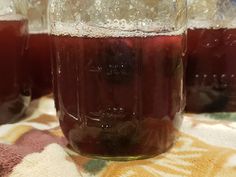 three jars filled with liquid sitting on top of a tablecloth covered table next to each other