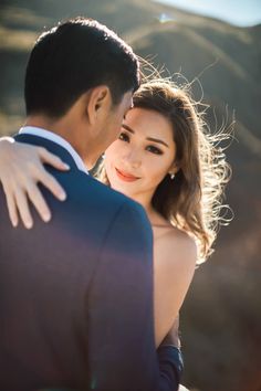 a man and woman embracing each other in front of mountains