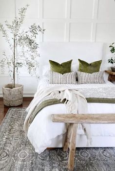 a bed with pillows and blankets on top of it next to a plant in a pot