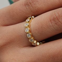 a woman's hand with a gold ring on top of her finger and diamond stones in the middle