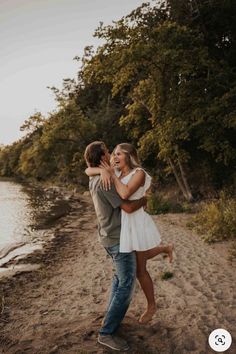 a man and woman hugging on the beach with trees in the backgroung