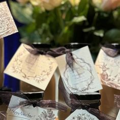 wedding favors are tied with brown ribbon and placed in small vases next to flowers