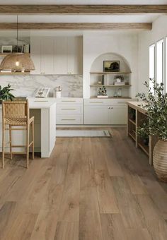 an open kitchen with white cabinets and wood flooring, along with a wooden dining table