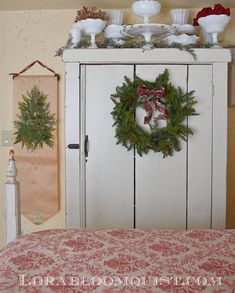 a white cabinet with wreaths on top of it