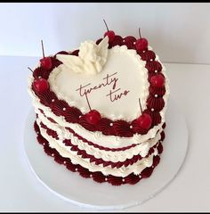 a heart shaped cake with the words twenty twos written on it and cherries