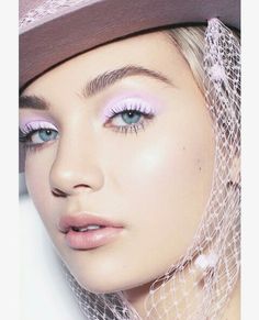 a close up of a woman wearing a hat and pink eye shadow with veil on her head