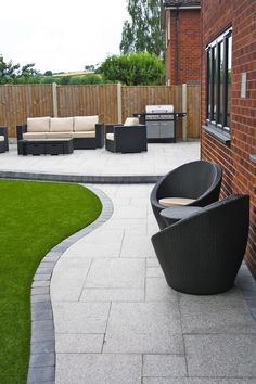 an outdoor patio with black furniture and grass