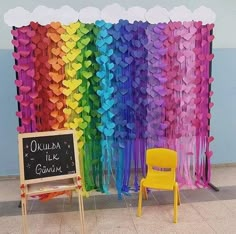 a rainbow colored backdrop with chairs and a chalkboard