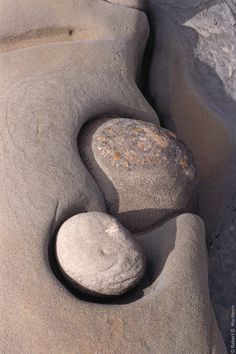 two rocks sitting on top of a sandy beach