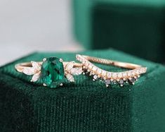 an emerald colored ring sitting on top of a green velvet box with diamonds around it