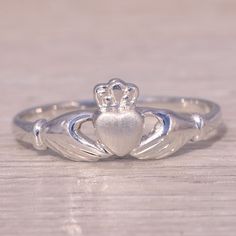 This Stunning Piece, Known As The Claddagh Embrace, Features The Iconic Claddagh Design, Symbolizing Love, Loyalty, And Friendship. The Heart, Crowned With A Regal Crown And Held By Two Hands, Represents The Timeless Sentiment Of Devotion. Crafted In 14 Karat White Gold, The Sleek And Polished Design Adds A Modern Touch To This Traditional Symbol. The Ring Is Crafted In 14 Karat White Gold And Is Currently A Finger Size 6.75 Yet Can Be Adjusted To Any Finger Size For An Additional Charge Upon Request, Ensuring A Perfect Fit. Gold Claddagh Ring, Claddagh Ring, Claddagh Rings, Womens Jewelry Rings, Two Hands, Perfect Fit, Sleek, White Gold, Crown