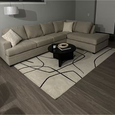 a living room with a sectional couch and coffee table on the rug in front of it