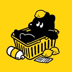 a black bear sitting in a yellow basket next to some bread and other food items