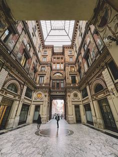 two people are walking through an ornately decorated building with high ceilings and glass windows