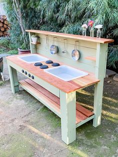 an outdoor kitchen made out of pallet wood with two sinks and pots hanging on the wall