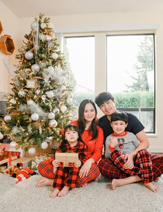 a family poses in front of a christmas tree