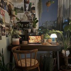 a desk with plants and pictures on the wall above it, along with a chair