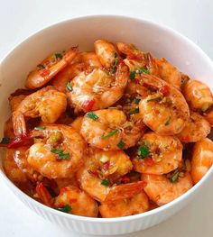 a white bowl filled with cooked shrimp on top of a table