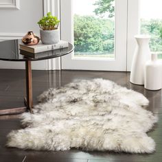 a table with a glass top and a white rug on the floor in front of it