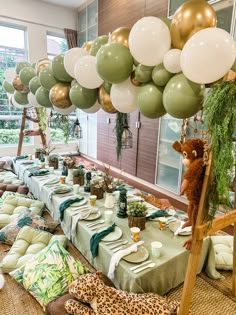 a table set up with green and gold balloons